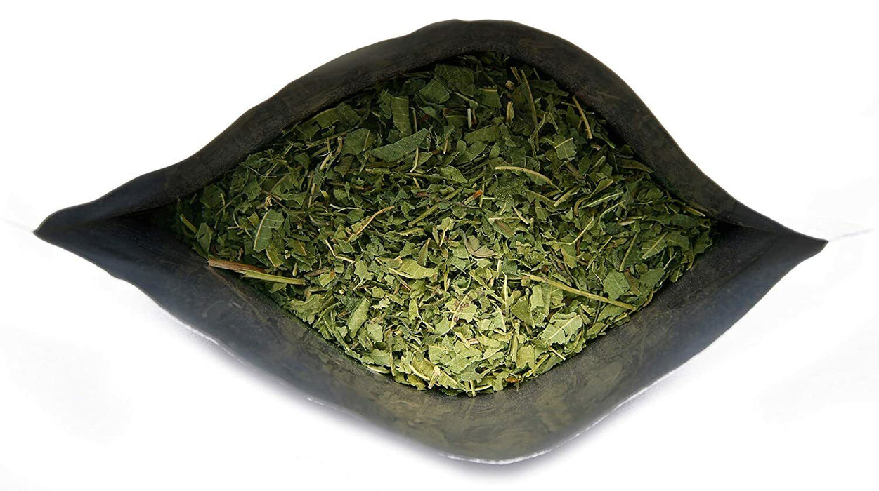 Paquet ouvert de thé de verveine citronnée sur fond noir montrant les feuilles séchées à l'intérieur.