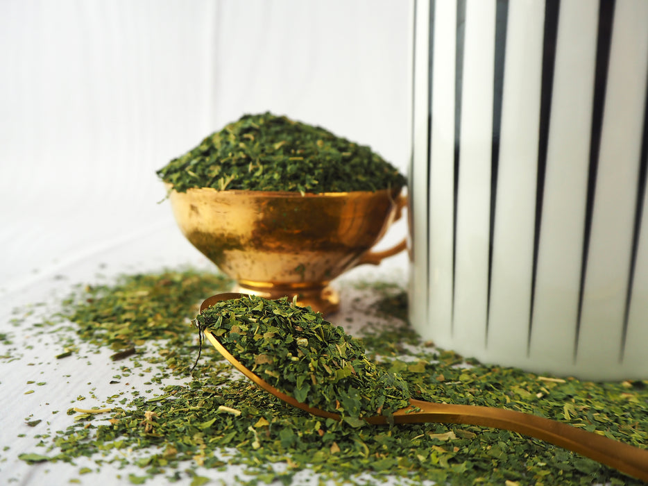 Feuilles de mûrier blanc séchées en vrac dans un bol doré, thé de qualité supérieure Morus alba pour infusions saines.