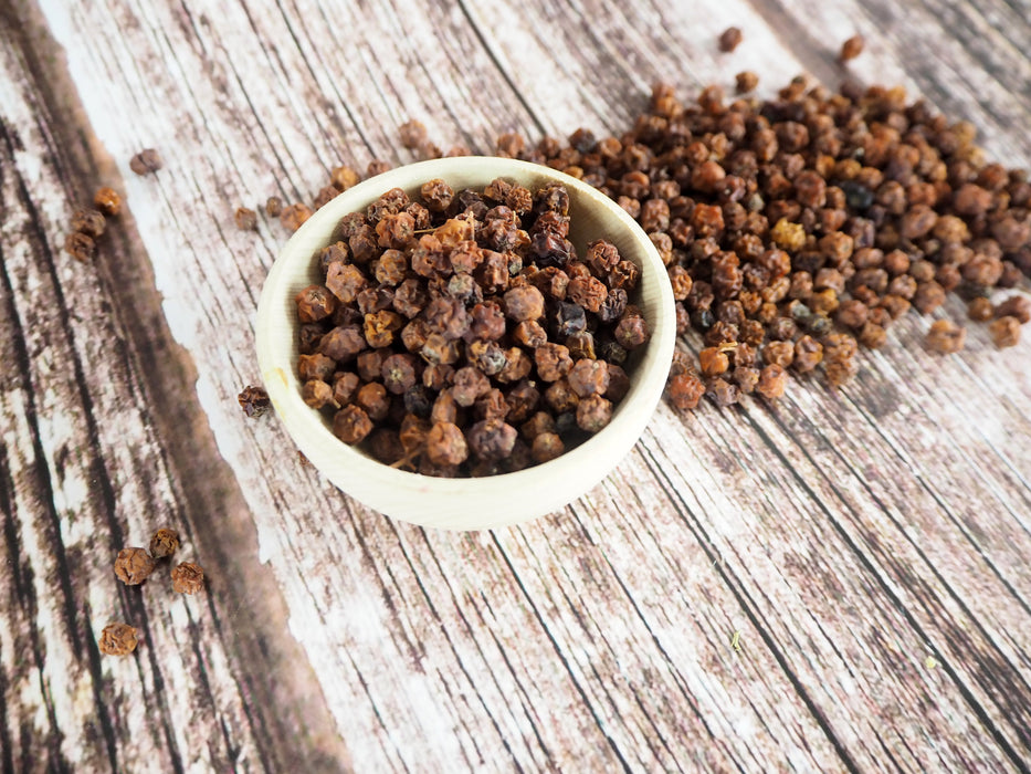 Baies de sorbier des oiseleurs dans un bol en bois rustique, prêtes à être consommées ou utilisées en infusion, source naturelle d'antioxydants.