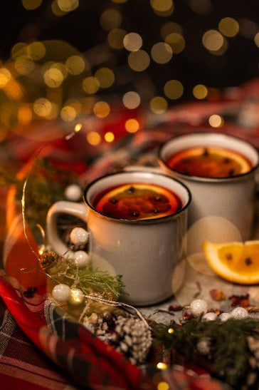 Deux tasses de thé chaud épicé entourées de décorations de Noël, créant une ambiance festive et chaleureuse.