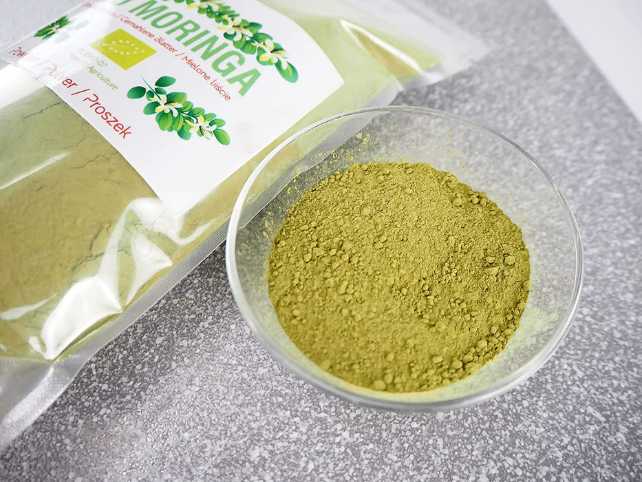 Poudre fine de Moringa Bio, riche en nutriments, sur fond en béton pour une alimentation saine et naturelle.