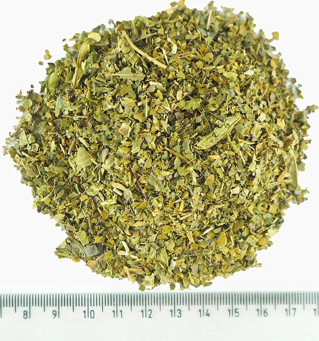 Mesure de Yerba Mate désamargée à la verveine citronnelle coupée finement à côté d'une règle pour montrer la granulométrie.