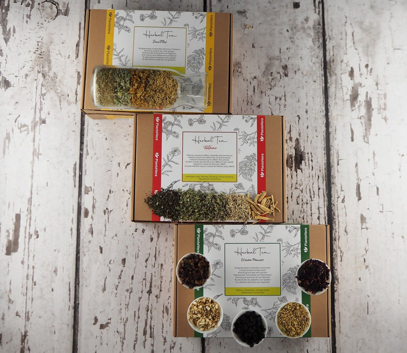 Coffrets cadeaux Herbal Tea Immuflos ouverts avec une variété de thés aux herbes sur fond rustique en bois.