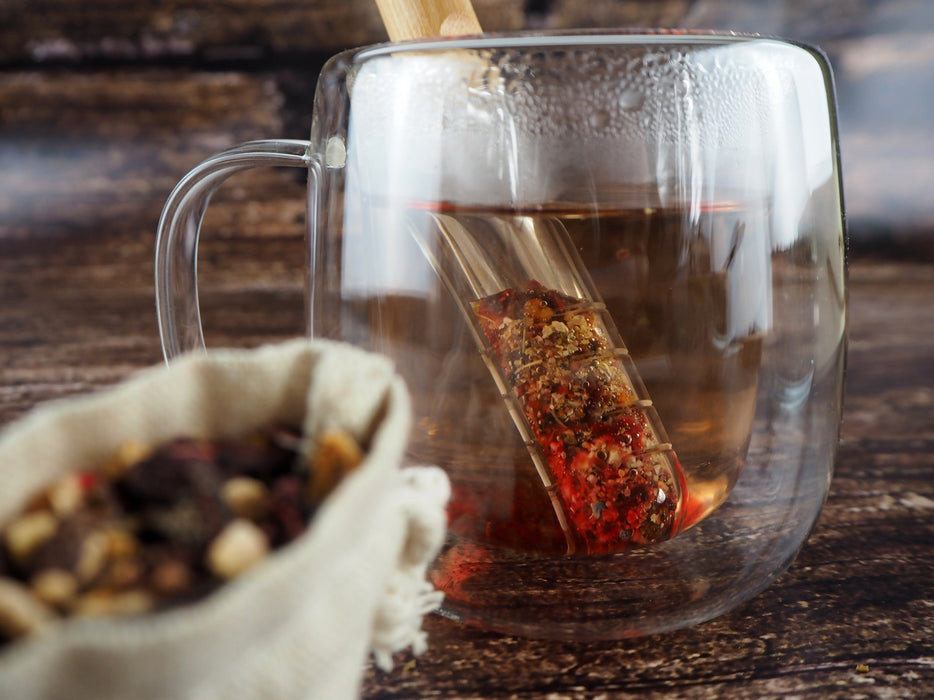 Infusion de thé rouge éclatante versée dans une tasse transparente, montrant la richesse des ingrédients.