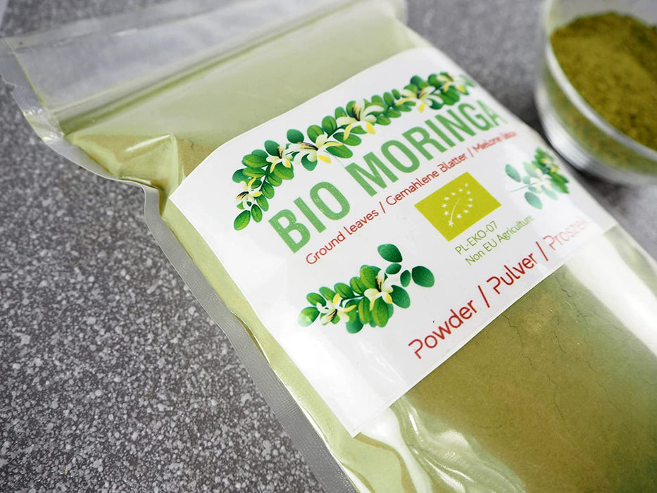 Moringa Bio en poudre à côté de son emballage, parfait pour les smoothies ou comme supplément alimentaire.