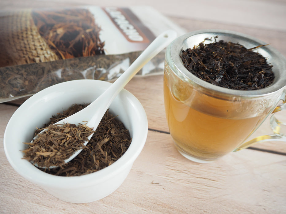 Une tasse de Thé Lapacho infusé à côté d'un sachet ouvert, évoquant la fraîcheur et l'authenticité de l'infusion traditionnelle.