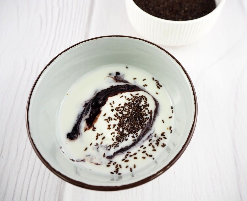 raines de psyllium noir biologique dans une cuillère sur fond blanc, prêtes pour votre santé digestive.