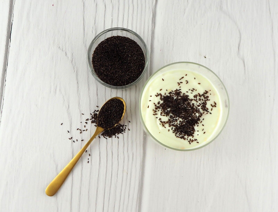 raines de psyllium noir biologique dans une cuillère sur fond blanc, prêtes pour votre santé digestive.