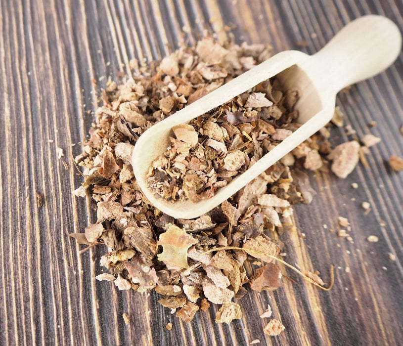 Cuillère en bois remplie de morceaux de Racine de Rhodiola Rosea séchée sur fond en bois rayé.