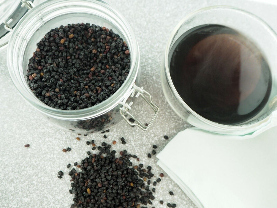 Baies de sureau séchées Fructus Sambuci, montrées dans un bocal en verre, mettant en avant leur qualité et texture pour l'épicerie fine.