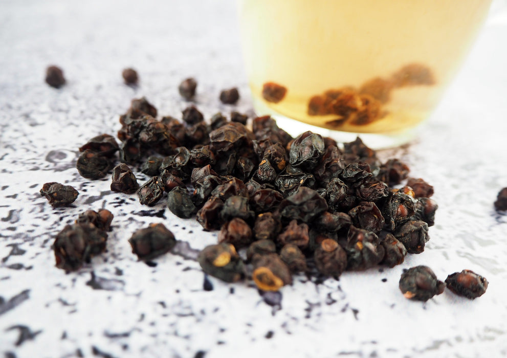 Focus sur les baies de Schisandra débordant de la tasse, soulignant leur potentiel aromatique et leurs bienfaits pour la santé en infusion.