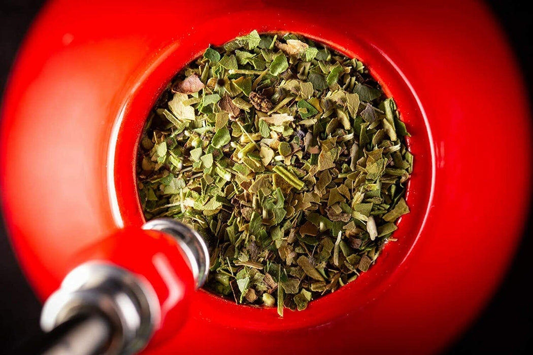 Infusion de Yerba Mate préparée dans une calebasse rouge éclatante, invitante à une expérience de dégustation authentique et dynamique.