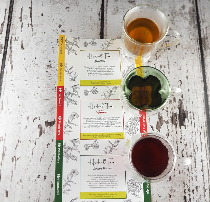 Divers thés Herbal Tea de PlantaVera disposés sur une table avec une tasse de chaque infusion, parfaits pour une pause hivernale.