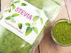 Poudre verte de Stevia dans un emballage transparent avec l'étiquette en plusieurs langues, indiquant un produit polyvalent et international.